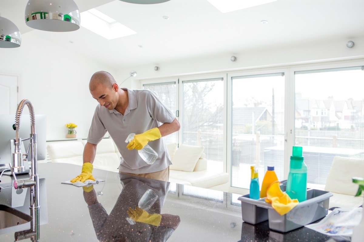 A professional cleaner polishing a kitchen counter in a bright, spotless home